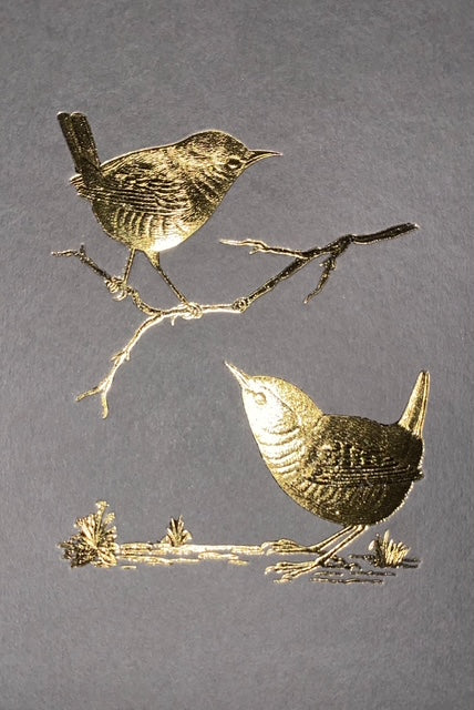 Two metallic birds on branches against a gray background