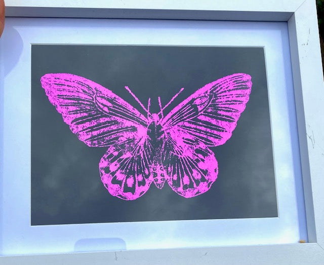 Framed artwork with a pink butterfly design on a dark background